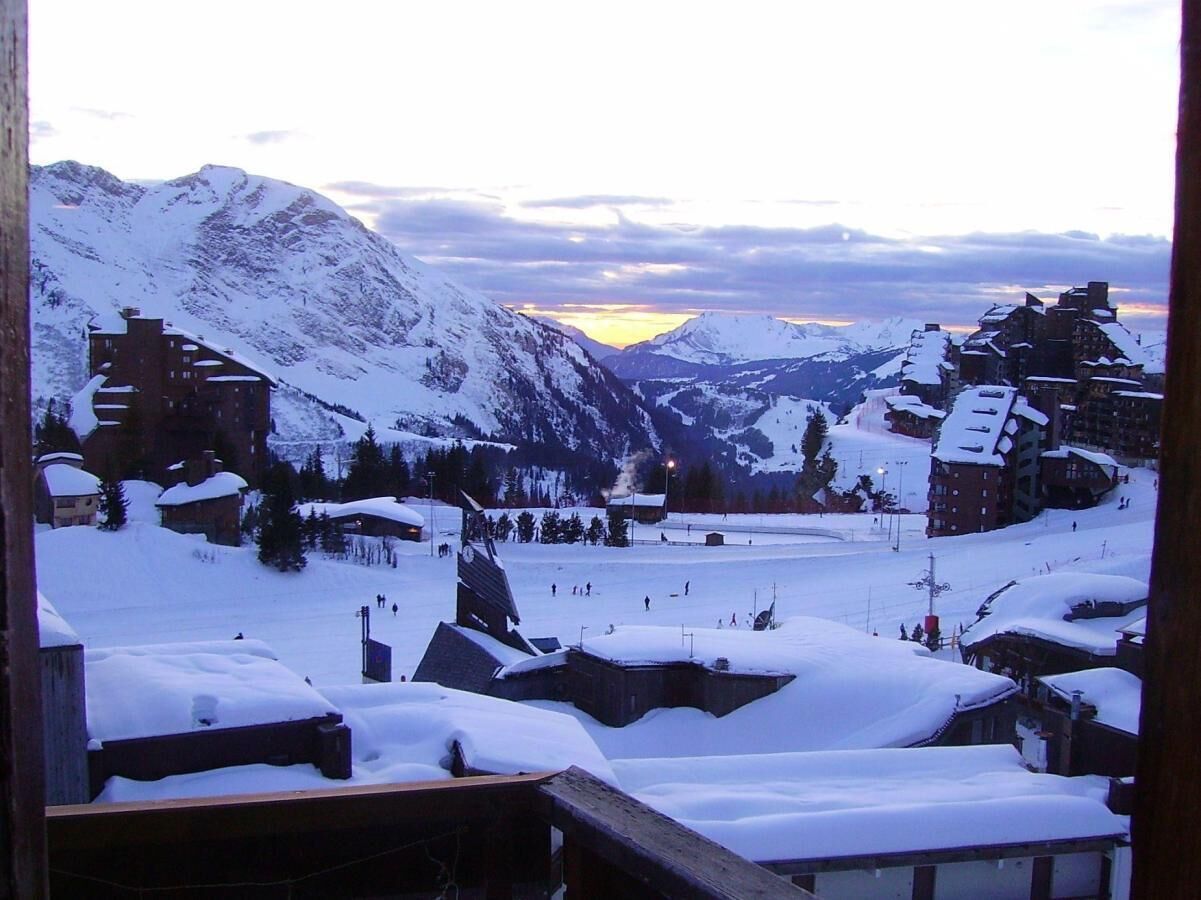 A snowy mountain village with buildings and a ski slope.