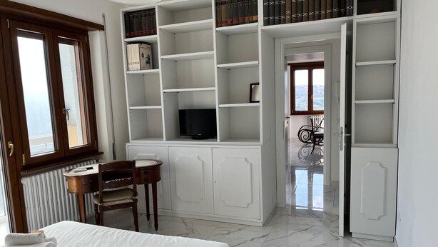 A hotel room with a bed, a desk with a chair, a television, and a bookshelf. - Three bedrooms, two bathrooms near St peter's Cathedral Area (Roma)