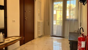 A hotel room with a wooden door, a radiator, a window with sheer curtains, a marble floor, and a fire extinguisher. - Three bedrooms, two bathrooms near St peter's Cathedral Area (Roma)