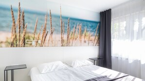 A modern bedroom with a large bed, a nightstand, and a wall-mounted lamp. - Hotel NOSPA (Kuressaare)