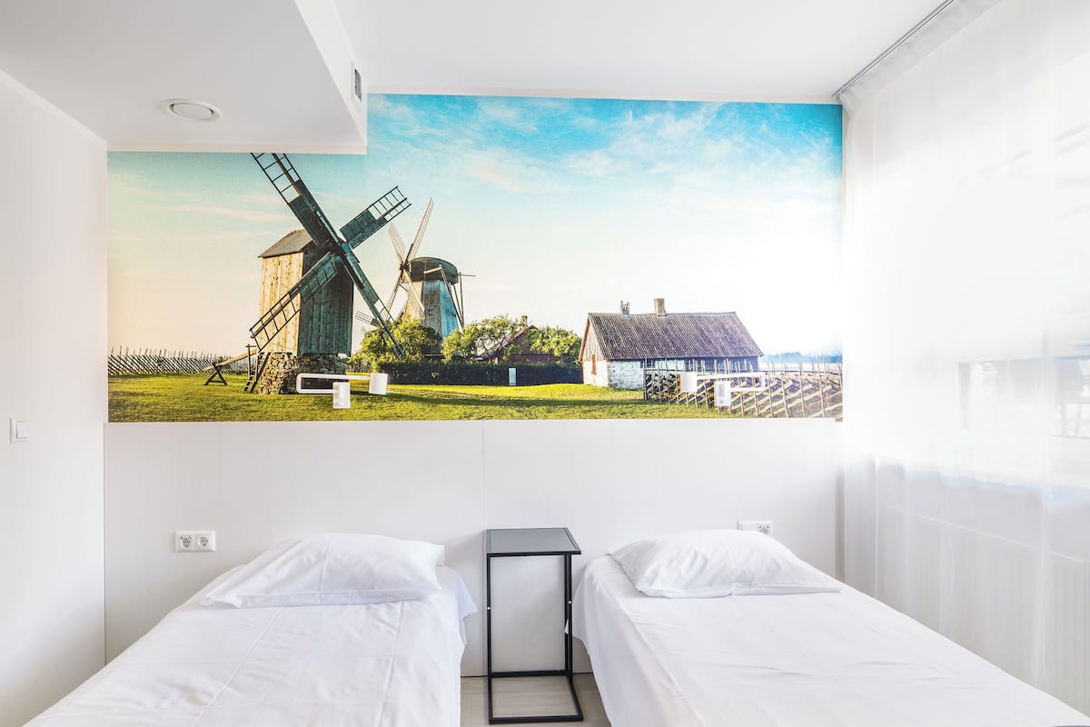 A hotel room with two beds, a view of windmills, and a large window.