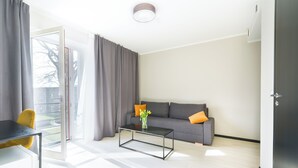 A modern living room with a grey sofa, a glass coffee table, and a yellow chair. - Hotel NOSPA (Kuressaare)