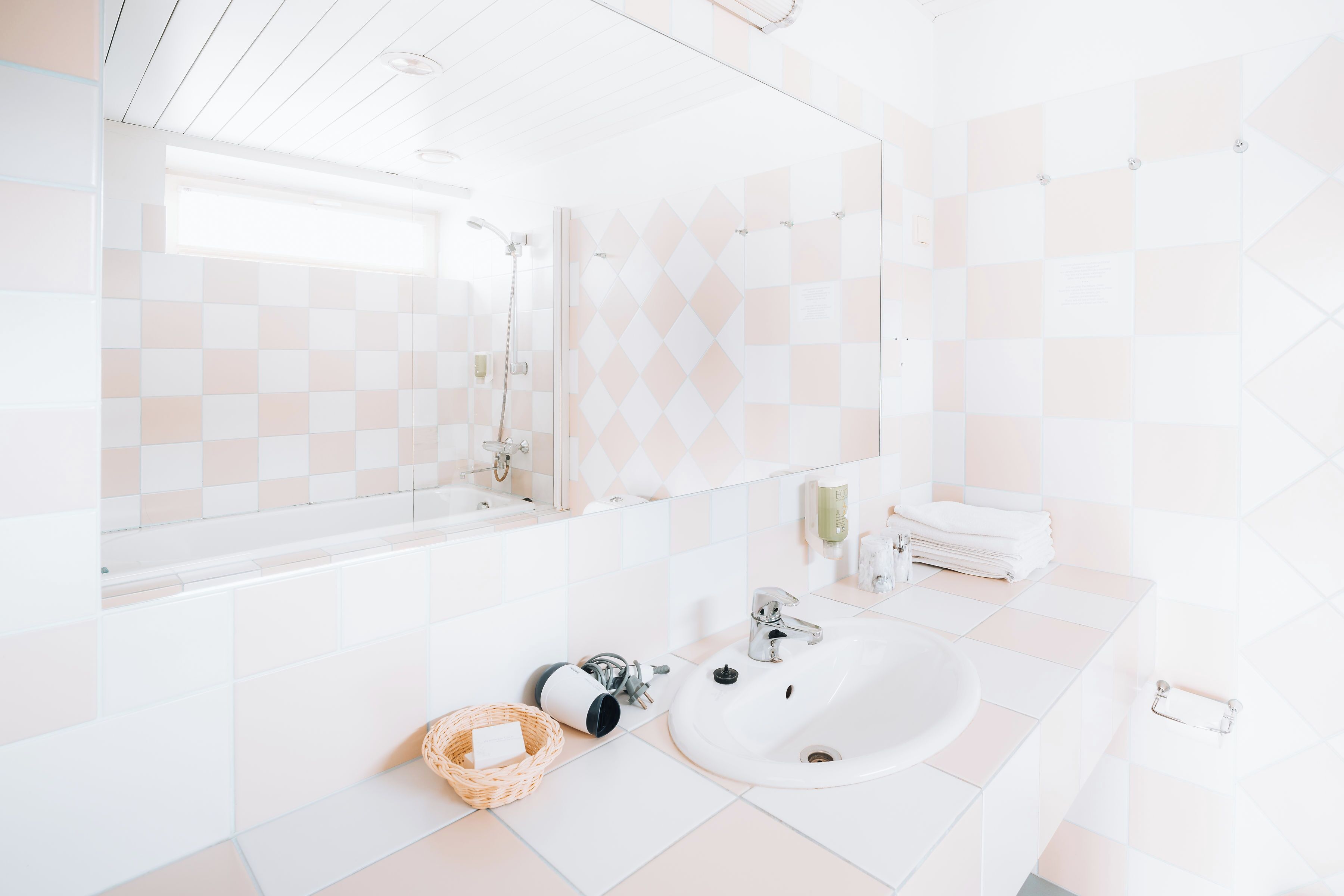 A modern bathroom with a white sink, a large mirror, and a checkered tile backsplash.