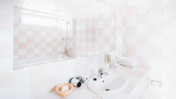 A modern bathroom with a white sink, a large mirror, and a checkered tile backsplash.