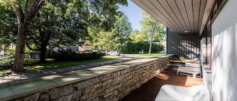 A covered outdoor area with a stone wall, wooden deck, and a bench.