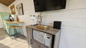 A kitchen with a microwave, a coffee maker, and a TV mounted on the wall.