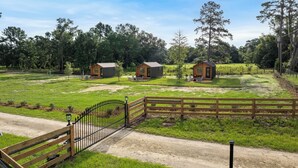 A rural property with three wooden cabins, a dirt road, and a metal gate.