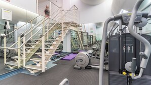A gym with a staircase, exercise equipment, and a mirrored wall.