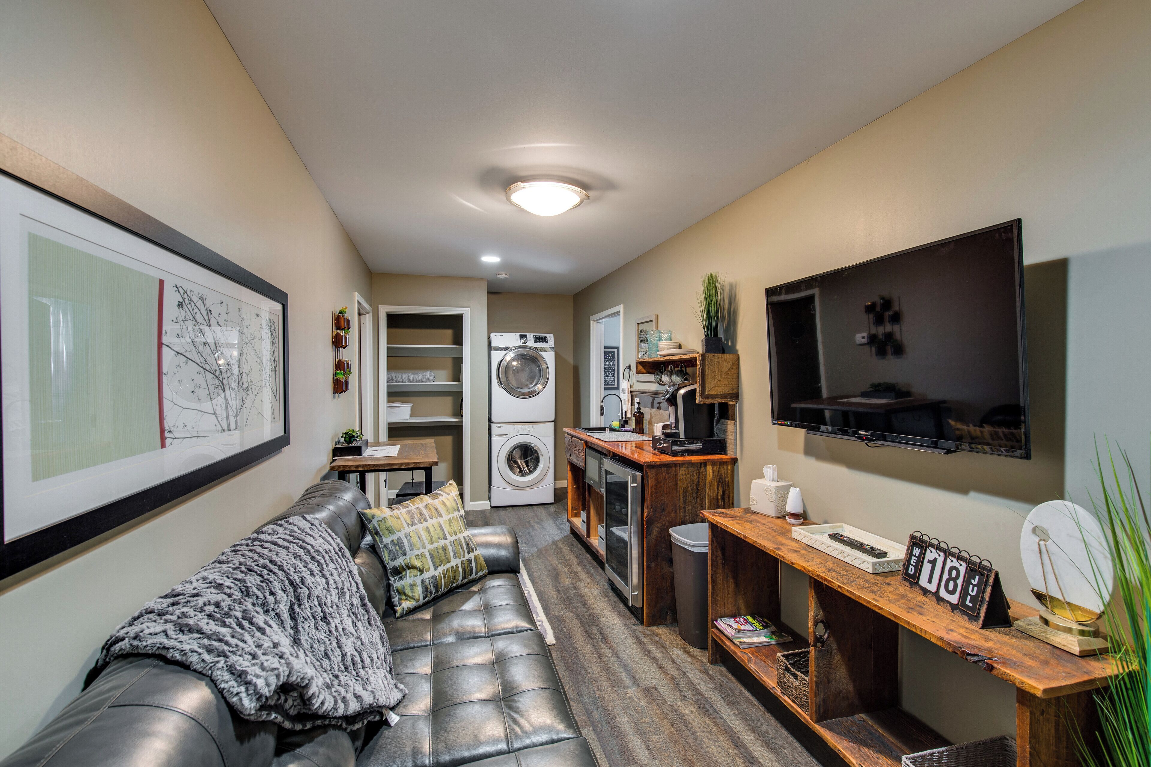 A compact living space with a sofa, a washing machine, a TV, and a calendar.