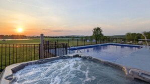 Una vasca idromassaggio con vista su un tramonto su un prato e una piscina.