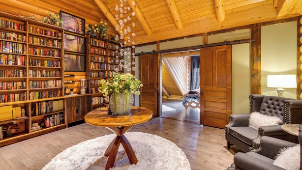 Una biblioteca accogliente con scaffali di legno, un tavolino con un vaso e una poltrona comoda.