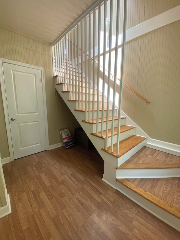 Una escalera con escalones de madera y barandillas blancas, que lleva a un piso superior.