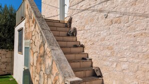 A stone staircase leading to a white door, surrounded by a stone wall and a small garden area. - High Accommodation in LocoMura (Locorotondo)