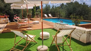 A poolside area with artificial grass, lounge chairs, and umbrellas. - High Accommodation in LocoMura (Locorotondo)