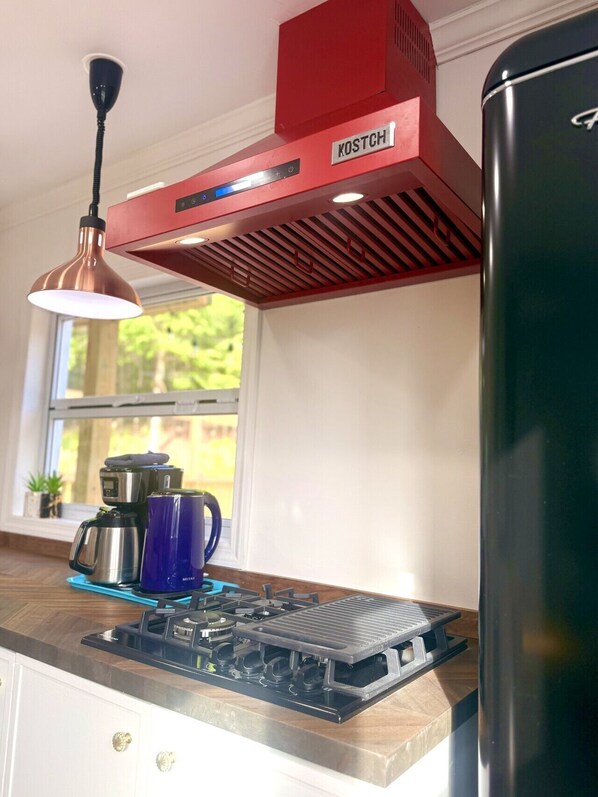 A kitchen with a red exhaust hood, a stainless steel stove, and a black refrigerator. - Catskills Apartment, Little Love Bird #5 (Highmount)