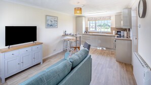 Een moderne keuken met een ingebouwde oven, een zithoek met een bank en een flatscreen-tv.