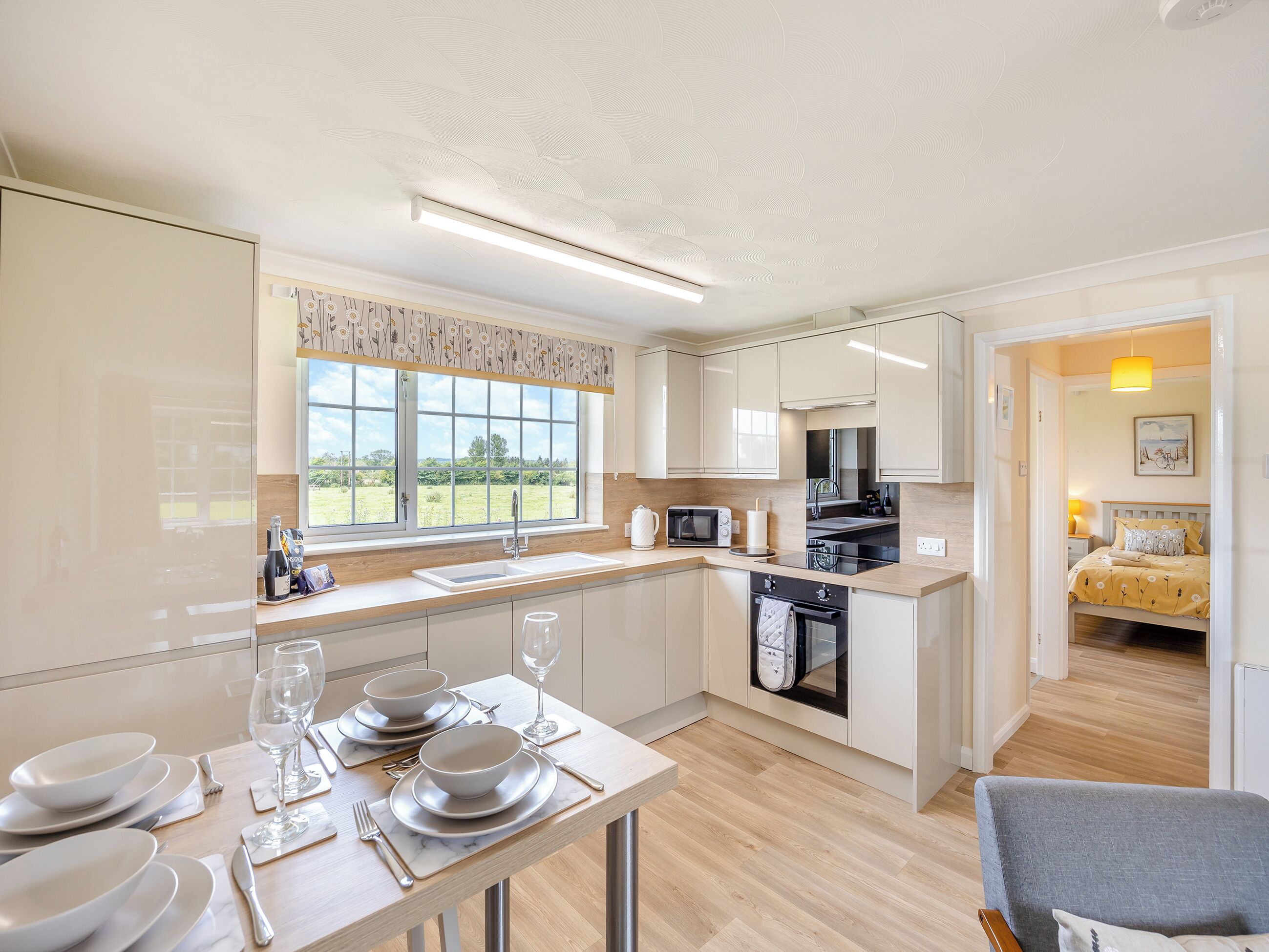 A modern kitchen with a dining area, large windows, and a view of the outdoors.