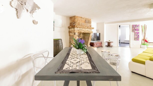 Un espacio de estar moderno con comedor, chimenea de piedra y sofá.