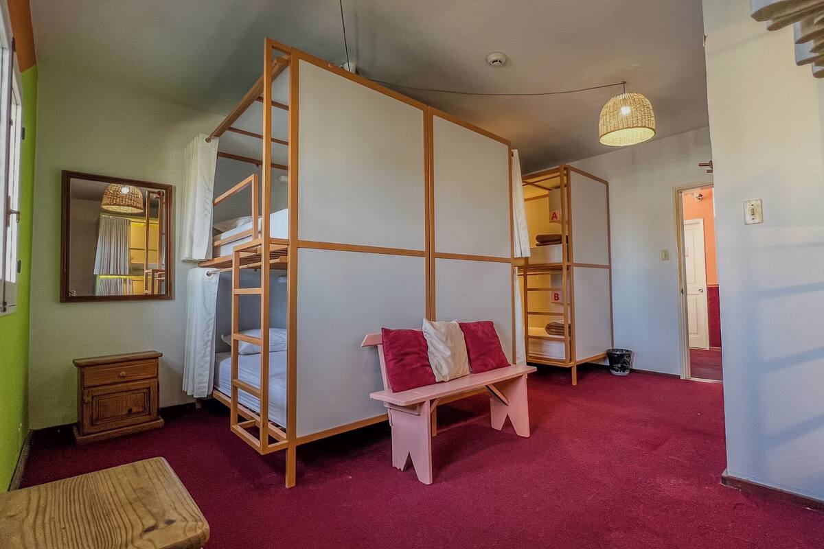 Een kamer met stapelbedden, een bankje, een kleine tafel en een hanglamp.