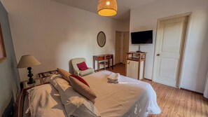 Een hotelkamer met een bed, een stoel, een bureau, een televisie en een deur.