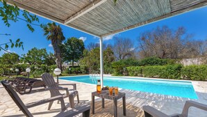 A poolside area with lounge chairs and a table with drinks.
