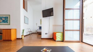Ein modernes Wohnzimmer mit einem schwarzen Couchtisch, einem an der Wand montierten Fernseher und einer Glastür, die zu einem Außenbereich führt.