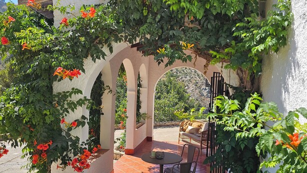 A covered patio with a table and chairs, surrounded by arches and lush greenery. - Villa Finca el Carril, Geweldige Locatie! (Vélez de Benaudalla)