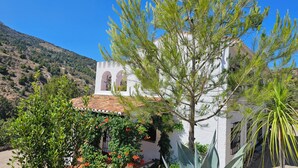 A white building with a tiled roof and arched windows, surrounded by greenery and a mountainous backdrop. - Villa Finca el Carril, Geweldige Locatie! (Vélez de Benaudalla)