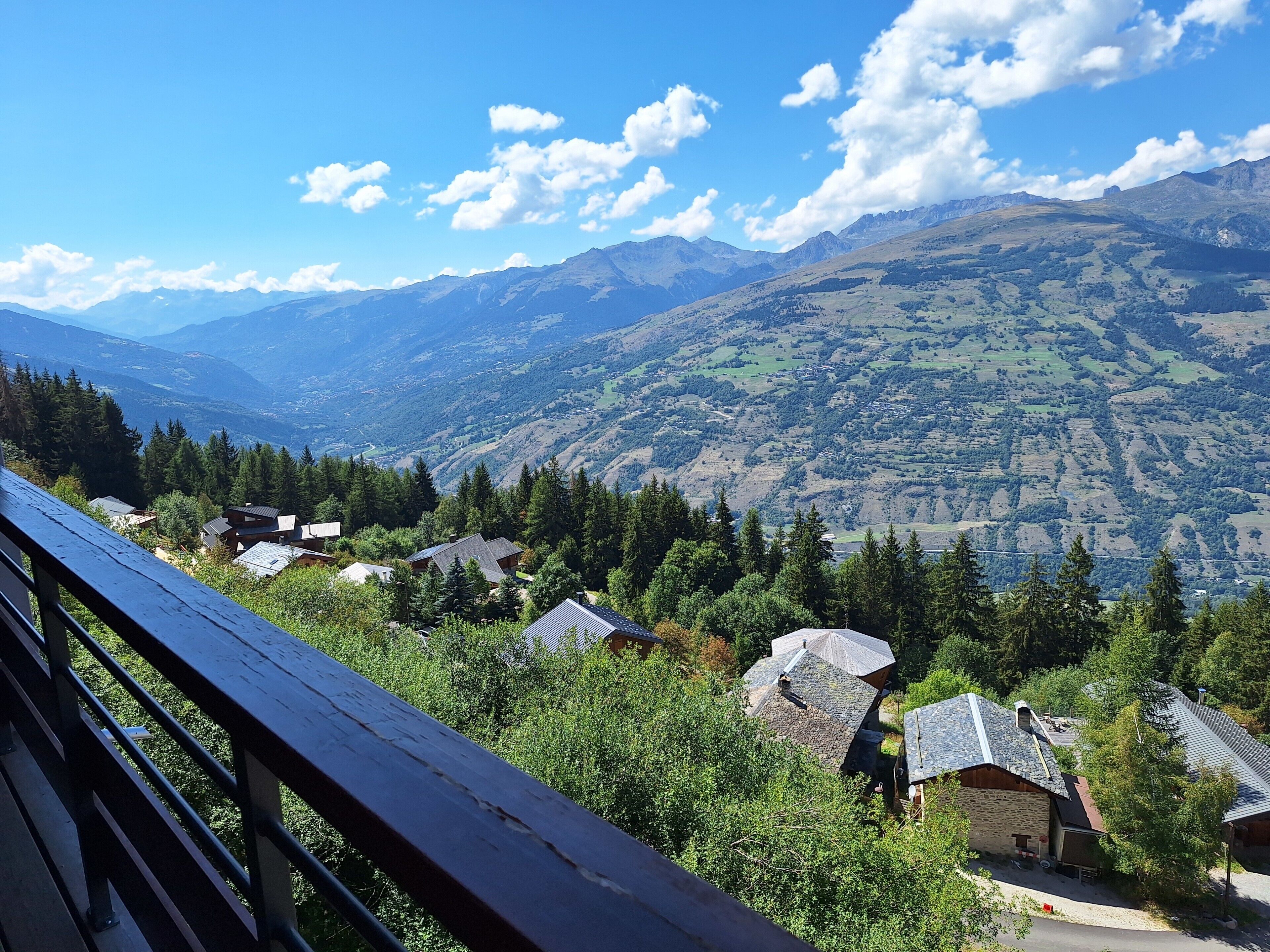 A mountainous landscape with a wooden deck overlooking a village with traditional houses.