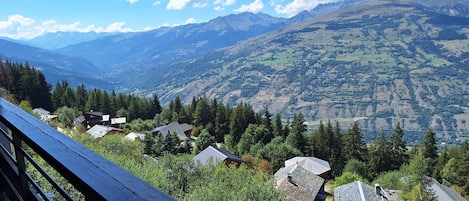 A mountainous landscape with a wooden deck overlooking a village with traditional houses.