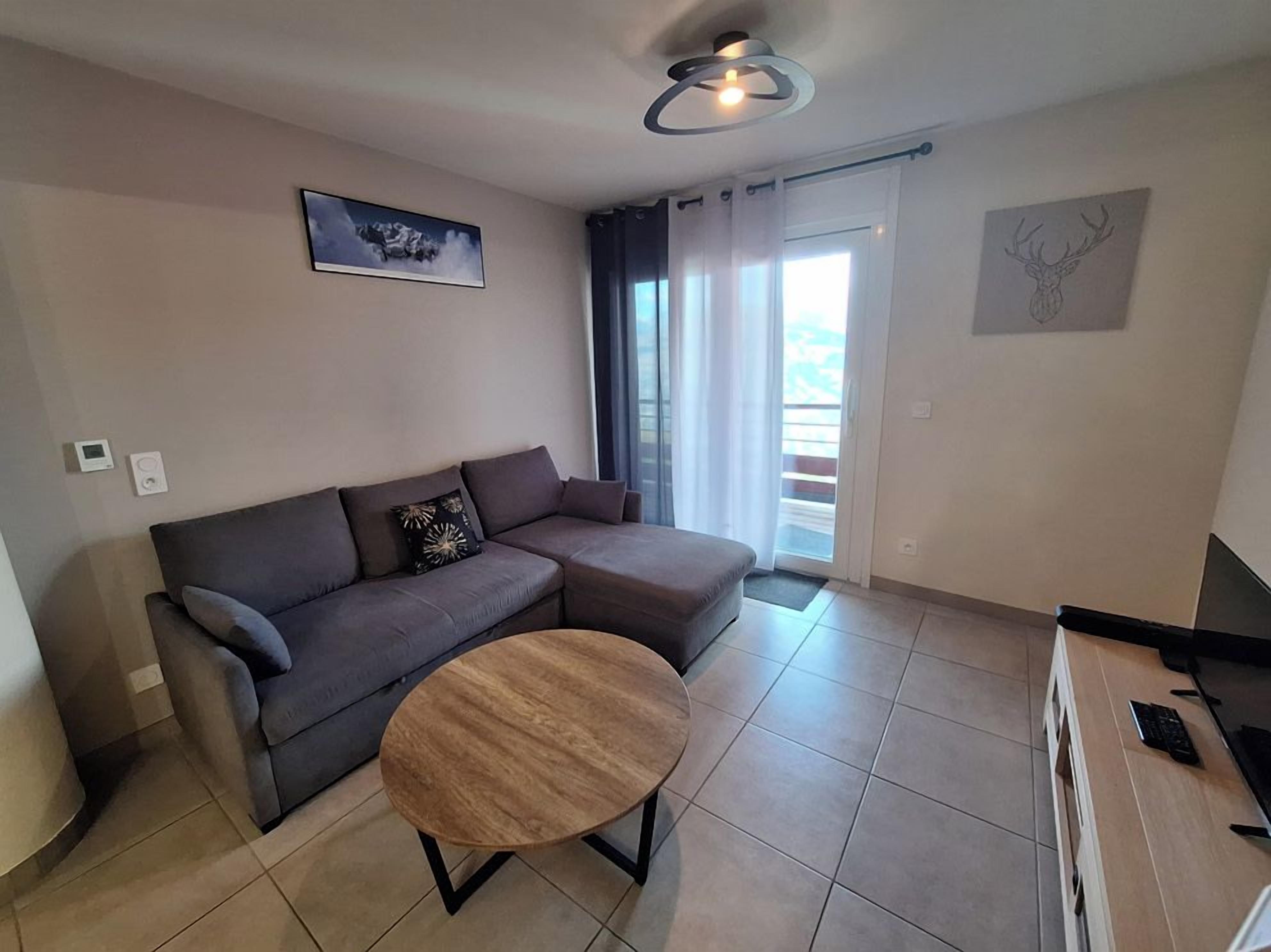 A modern living room with a sectional sofa, a round coffee table, and a flat-screen TV.