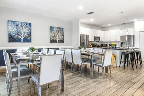 Una cocina moderna con armarios blancos, electrodomésticos de acero inoxidable y una isla central.