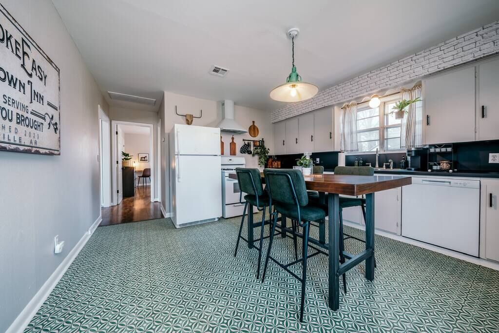 Una cocina moderna con armarios blancos, una mesa de comedor con sillas y un piso con diseño.