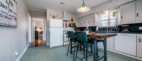 Una cocina moderna con armarios blancos, una mesa de comedor con sillas y un piso con diseño.