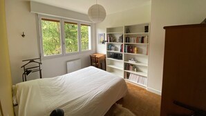 Une chambre à coucher avec un lit, un bureau, une bibliothèque et un radiateur.
