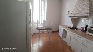 Una cucina con mobili bianchi, un fornello a gas, un forno a microonde e una finestra con tende.