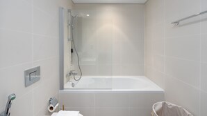 Ein modernes Badezimmer mit einer gläsernen Dusche, einer freistehenden Badewanne und einem WC.