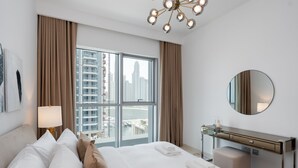 Ein Hotelzimmer mit einem großen Bett, einem Schreibtisch, einem Spiegel und Blick auf die Stadt.
