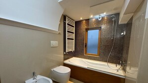 Ein modernes Badezimmer mit Bidet, Toilette und Badewanne.
