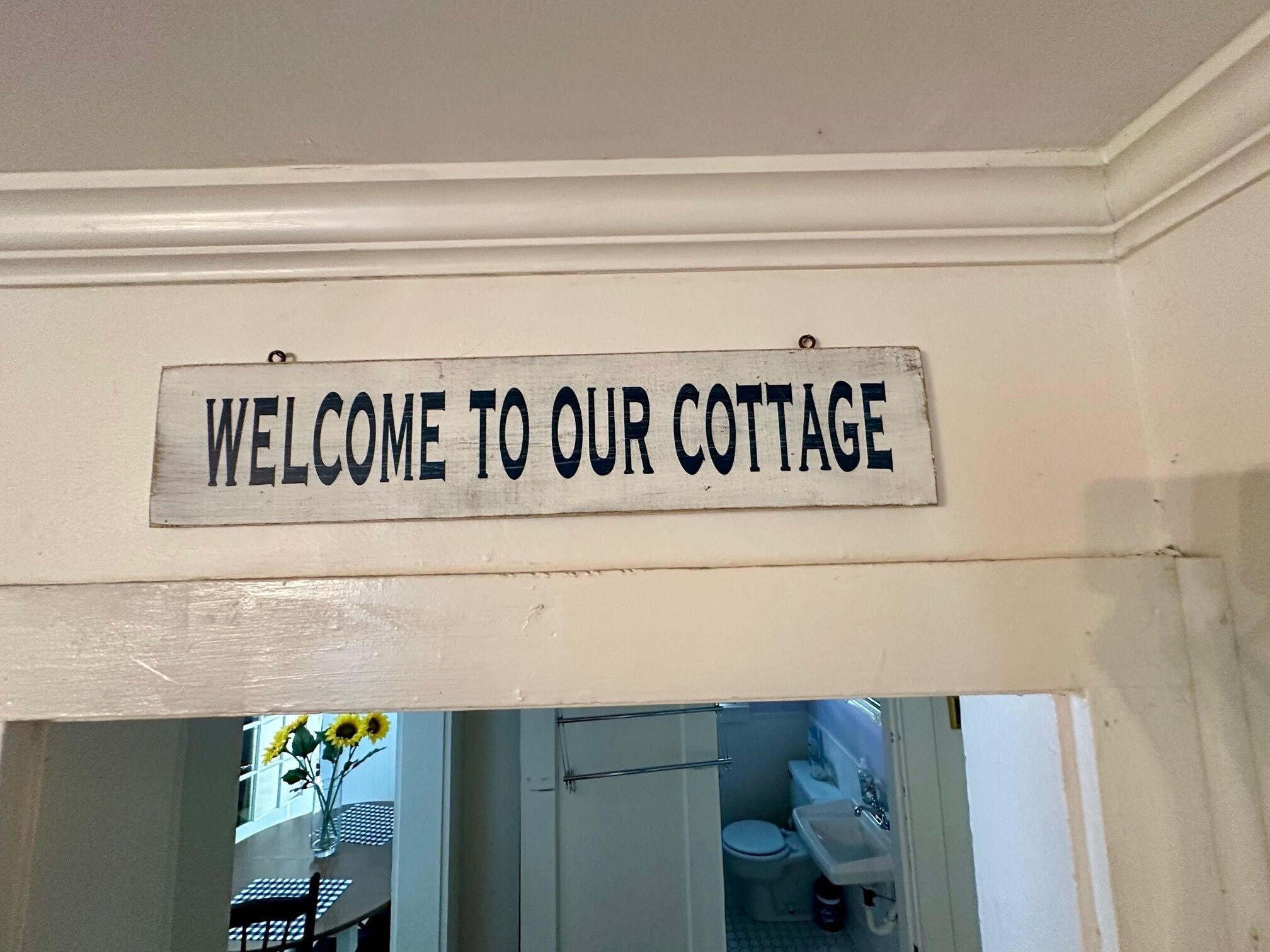 Un cartell que diu "BENVINGUTS A LA NOSTRA CABAÑA" sobre una porta que dona a un espai interior.