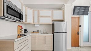 A modern kitchen with a stainless steel refrigerator, a microwave, and wooden cabinets. - New! Penthouse Studio C in heart of Condado (San Juan)