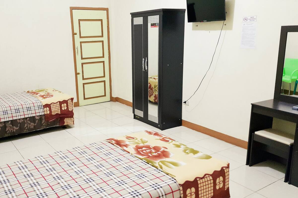 A room with two beds, a desk, a television, and a door.