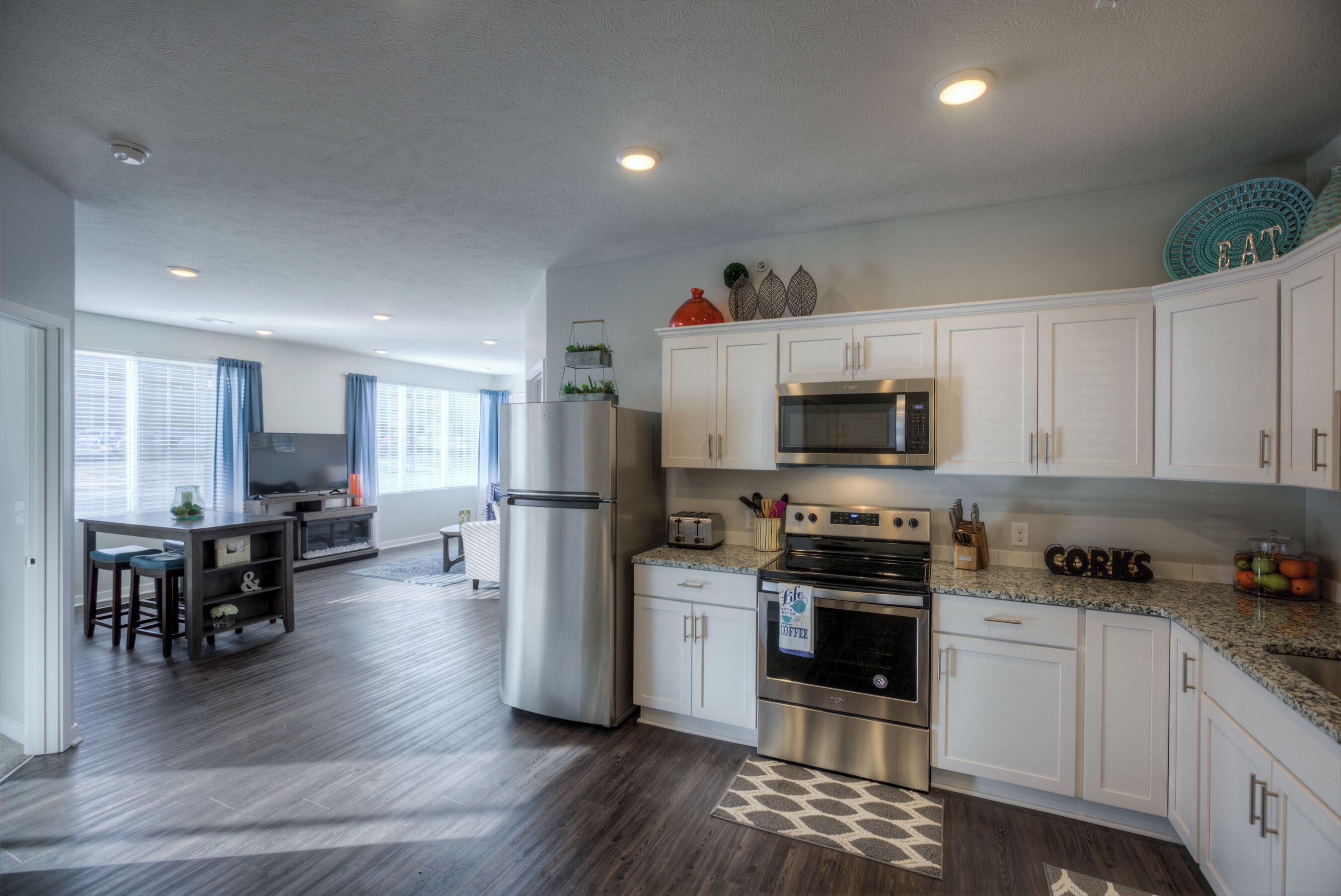 A modern kitchen with white cabinets, stainless steel appliances, and a granite countertop.