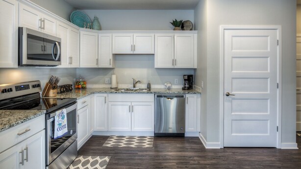A modern kitchen with white cabinets, stainless steel appliances, and a granite countertop. - Cozy 2-Bedroom Condo in Vibrant Urban Omaha with Convenient Designated Parking (Omaha)