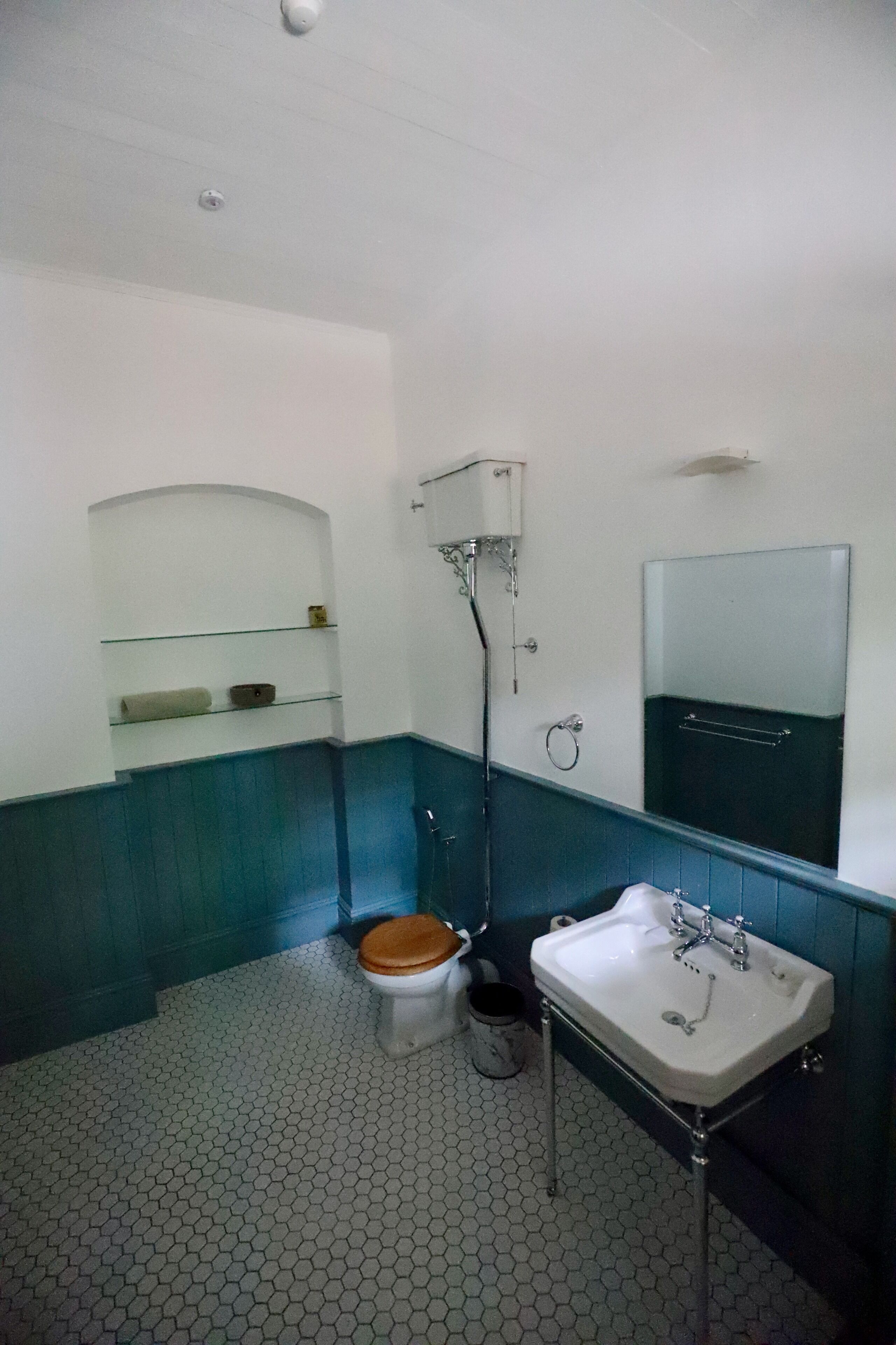 A bathroom with a toilet, sink, and mirror.