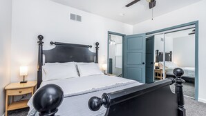 A bedroom with a bed, nightstands, a ceiling fan, and a door leading to another room. - Cheerful home by Millwork District/Farmers Market (Dubuque)