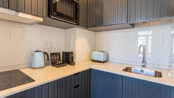 Une cuisine moderne équipée d’un four à micro-ondes, d’un grille-pain et d’une machine à café intégrés dans le plan de travail.