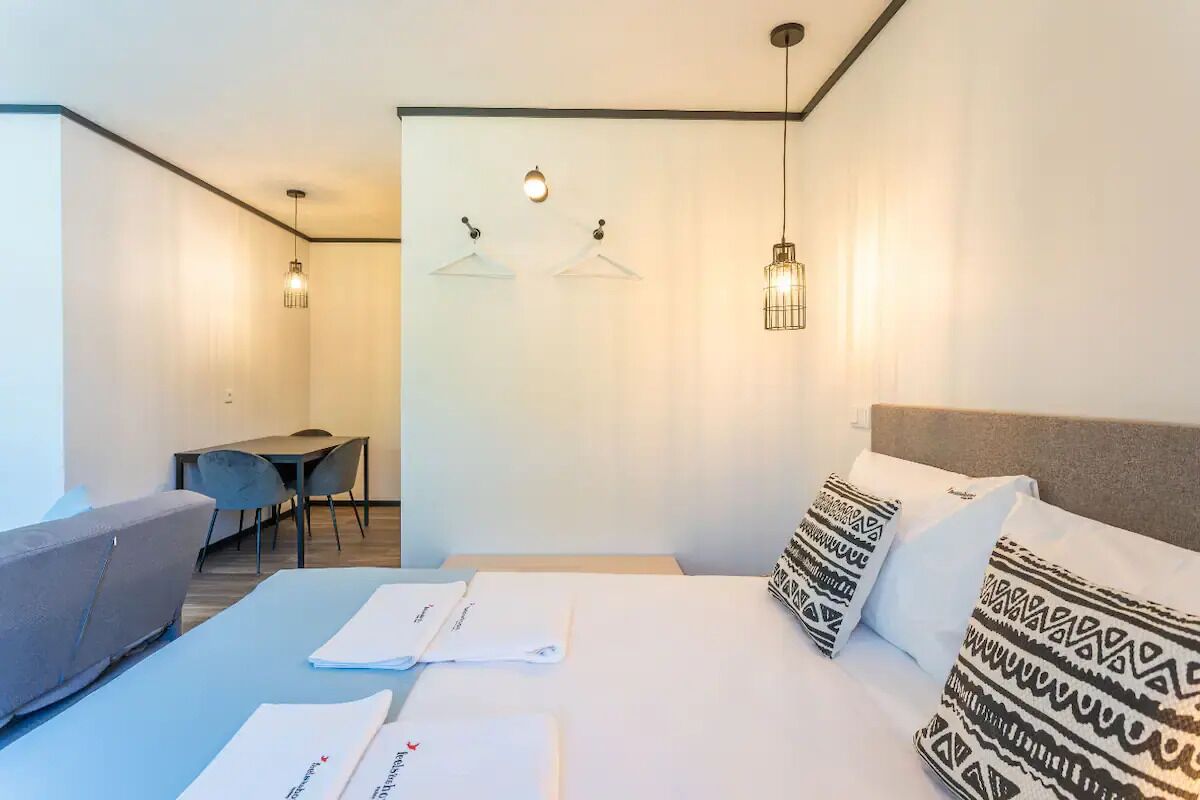 A modern hotel room with a bed, a desk, and two chairs.