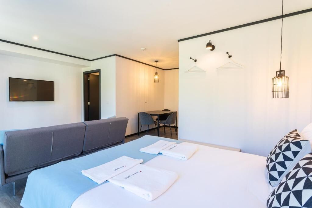 Une chambre d’hôtel moderne équipée d’un lit, d’un canapé, d’un bureau et d’une télévision.