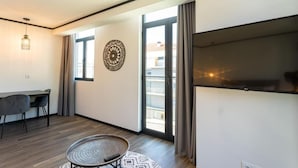 Un salon moderne comprenant un coin repas, une grande fenêtre et un téléviseur à écran plat.